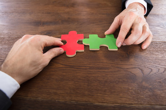 Two Businessmen Joining Jigsaw Pieces