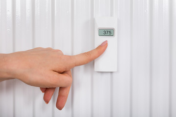 Person Adjusting Temperature With Digital Thermostat