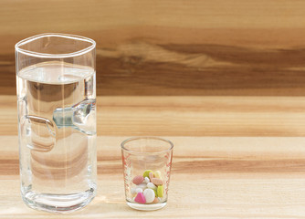 pills medicine and glass of water on wooden background.