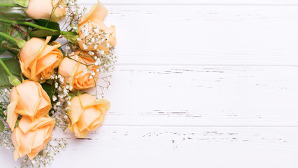 Obraz premium Border from peach color roses flowers on white wooden background.