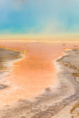 Rising blue steam and mist from Grand Prismatic hot spring in Midway Geyser basin at Yellowstone National Park with red bacterial patterns
