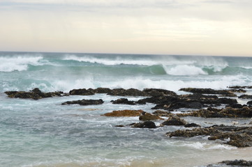 Sunset over the ocean, with waves breaking over the rocks