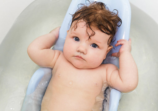 Little baby swims in the bathtub.