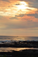 Fototapeta premium Sunset over the ocean, with waves breaking over the rocks
