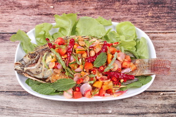 Spicy and sour fried Tilapia Salad with baby tamarind leaves .