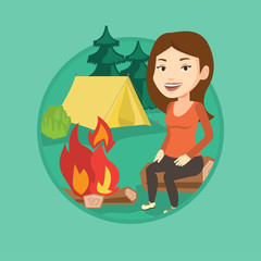 Woman sitting on log near campfire in the camping.