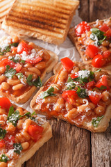Delicious toast with white beans, tomatoes, cheese and herbs closeup. vertical