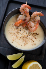 Close-up of cream-soup with potato and king shrimps, studio shot