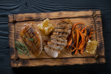 Wooden serving tray with whole and sliced fried duck breasts