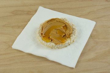Snack of peanut butter and honey om brown rice cake on napkin