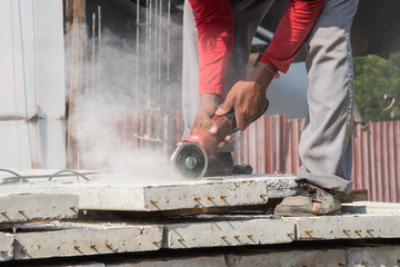 Builder worker with grinder machine cutting concreate floor at construction site