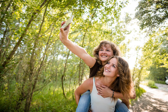 Mother and her teenager daughter  taking selfie with mobile phone