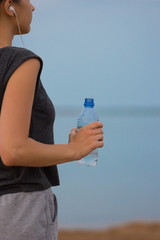 A bottle of water close-up. The girl drinks water during fitness outdoors. The girl drinks water...
