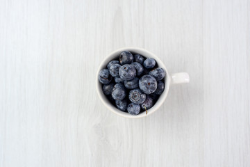 fresh blueberries in mug on wooden background.