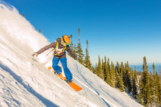 Freeride snowboarder slides down a steep slope at dawn