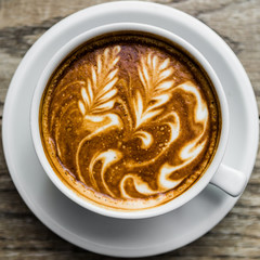 Latte art coffee on natural wood table.