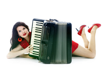 pretty woman lies with accordion on floor of studio with white background