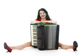 pretty woman sits with accordion on floor of studio with white background