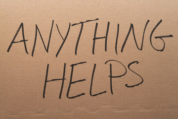 Thw words "Anything Helps" written on a carboard sign