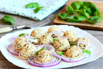 Cheese balls appetizer. Delicious cheese balls with dried herbs and roasted sesame seeds served with onion rings and basil on a plate. Easy and quick appetizer recipe. Rustic style