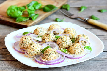 Small cheese balls on a plate. Cream cheese balls with dried herbs and roasted sesame seeds served with fresh onion rings and basil. Easy cheese snack food. Closeup