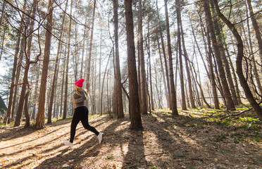 Girl wearing sportswear and running in forest at mountain