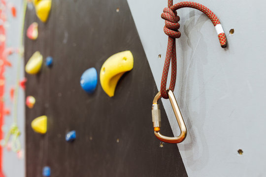Image of a carabiner hook with a climbing rope at indoors artificial climbing wall