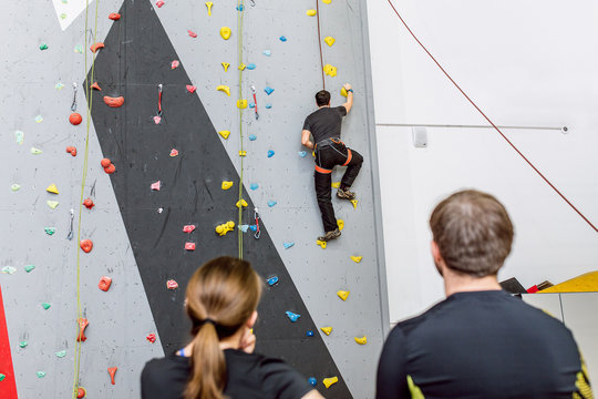 Fit Friends on the artificial climbing wall indoors discussing tactics of bouldering