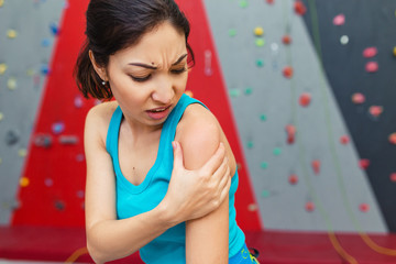 Athlete woman was traumatized and experiences severe pain in his shoulder after a climbing session on the bouldering wall