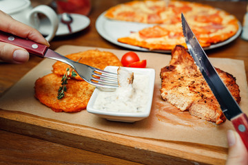 Woman eating with a fork and a knife pork steak in a restaurant