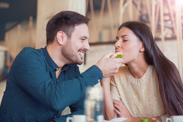 Beautiful young couple sitting in a cafe, having breakfast. Love, food, lifestyle concept