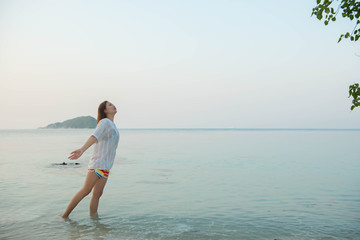 Happy woman standing arms outstretched  and enjoy life on the beach at Sea