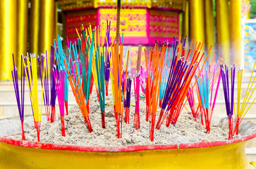 colorful of incense sticks burning in a golden pot at the temple