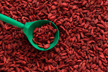 Green spoon in a pile of dried goji berry fruit