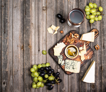 Grapes, red wine, cheeses, honey and nuts over rustic weathered wood. Top view with copy space.