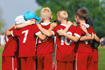 Naklejka premium Children Soccer Team. Children Football Academy. Kids Soccer Players in Red Shirts Standing Together on the Pitch. Youth Soccer Motivational Speech. Coach Motivational Talk With Young Boys