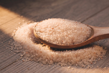 Himalayan pink rock salt in wooden spoon. Closeup. Sunny day