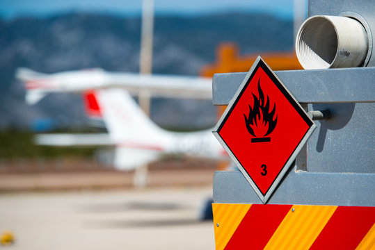 Rear view of service and refuelling truck on an airport with an aircraft in the blurry background. Chemical hazard, flammable liquids.