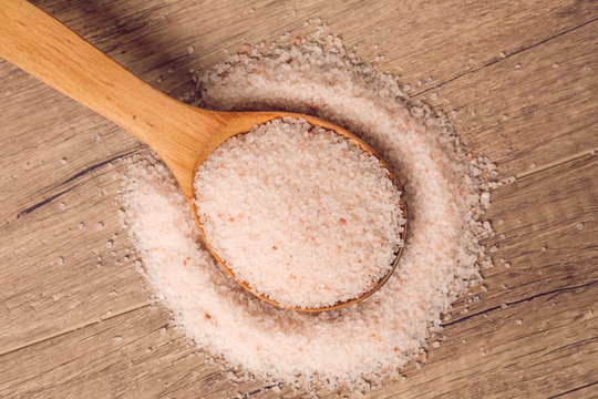 Himalayan salt on wooden spoon and wooden background. Top View.