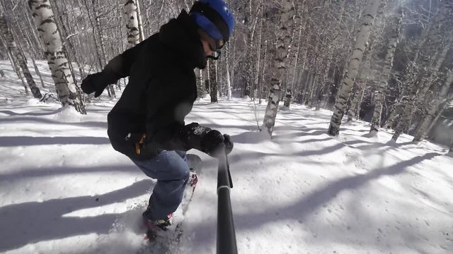 Slow motion footage of snowboarder man riding through the forest