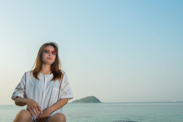 Fototapeta premium young woman happy sitting on the rock with the beach