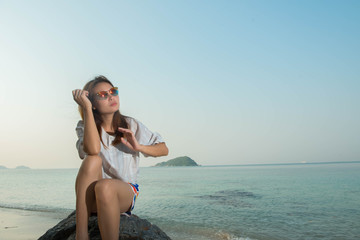 young woman happy sitting on the rock with the beach