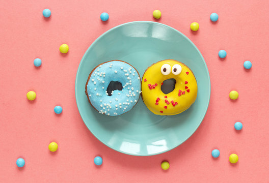 Funny donuts with icing on a blue plate.