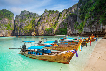 Thailand sea beach view round with steep limestone hills with many traditional longtail boats parking
