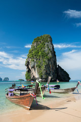 Colorful long tail boats at beautiful Ao Nang beach on a background of blue sky and azure sea and limestone rocks