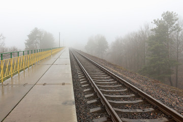 Fototapeta premium railroad goes into the mist. gray misty autumn morning.