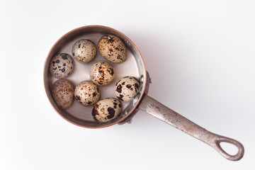 Quail eggs in an old pot. On a white background