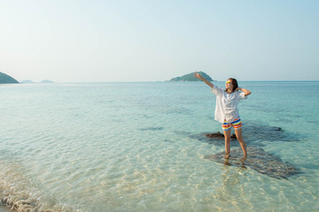 Happy woman standing arms outstretched on the beach at Sea