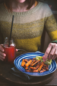Woman in a green sweater eating fried carrots