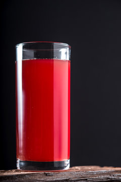 Cranberry drink in a tall glass on a black background